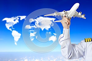 Captain holding airplane model against clouds in shape of world map concept for travel around the world