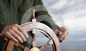 Captain holding hand on ship rudder.