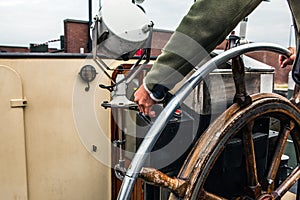 Captain operate an ancient ship steering wheel.