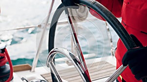 Captain`s hands are managing yacht`s steering wheel