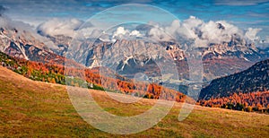 Captivating autumn scene of Dolomite Alps with foggy mountain range on background.