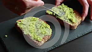 A captivating close-up video of someone spreading creamy avocado onto a slice of toast bread