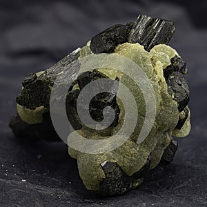 This captivating specimen features prehnite\'s botryoidal texture and glowing green hue, accented by dark mineral inclusions photo