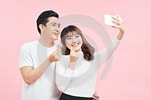 Capture happy moments together. Happy young loving couple making selfie and smiling while standing against grey background