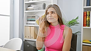 Capture the moment, young, beautiful hispanic female professional, engrossed in work, intently listening to voice message on