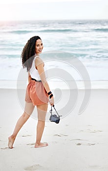 Capturing the beauty in life. a young woman taking pictures at the beach.