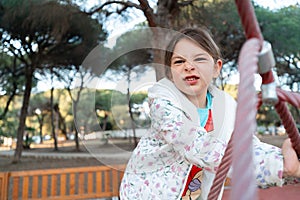 Capturing a child's playful side, this image shows a young girl making a face while navigating a rope course at a