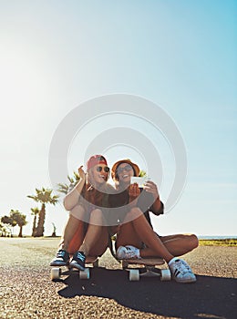 Capturing summer memories. two friends hanging out on the boardwalk with a skateboard.