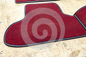 Car 3D handmade floor mats of red color from wool for front and rear passengers of a vehicle in an interior design workshop with