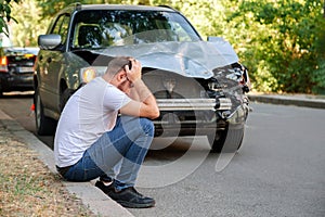 Car accident. Man holding his head after car accident. Man regrets damage caused during car wreck. Man driver is