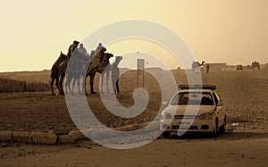 Car and Arabs on camels in the desert of Egypt