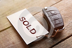 Car auction Sold out concept. Vehicle security key with tag on the wooden background