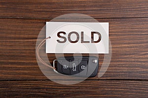 Car auction Sold out concept. Vehicle security key with tag on the wooden background