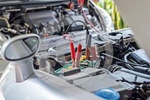 car battery clamped with black and red jumper cable to recharge