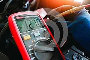 Car battery voltage testing with a digital multimeter by auto technician