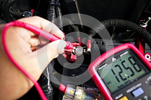 Car battery voltage testing with a digital multimeter by auto technician