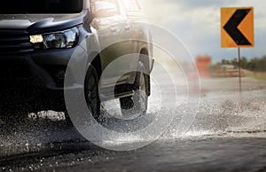 Car with big puddle of water spray from the wheels  through flood water after hard rain.