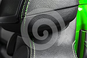 Car black leather interior. Part of leather car seat details with green stitching. Interior of prestige modern car. Comfortable pe