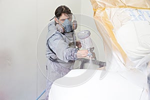 Car body painter spraying paint on bodywork parts