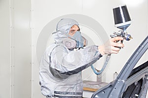 Car body painter spraying paint on bodywork parts