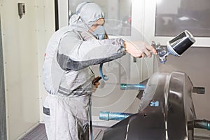 Car body painter spraying paint on bodywork parts