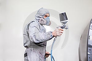 Car body painter spraying paint on bodywork parts photo