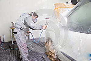 Car body painter spraying paint on bodywork parts photo