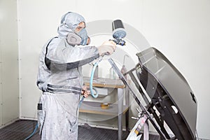 Car body painter spraying paint on bodywork parts photo