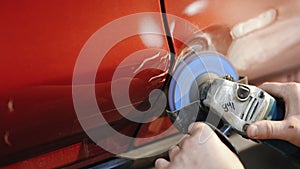 Car body panel repairing on the garage, car door panel dent removing. Auto repairman grinding automobile body. Accident