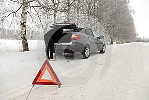 Car breakdown on the highway in winter. Sign on an emergency stop.