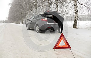 Car breakdown on the highway in winter. Sign on an emergency stop.