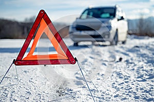Car breakdown on a road in winter. Winter driving. Warning triangle on the road, waiting for help.
