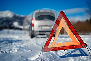 Car breakdown on a road in winter. Winter driving. Warning triangle on the road, waiting for help.