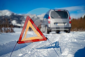 Car breakdown on a road in winter. Winter driving. Warning triangle on the road, waiting for help.