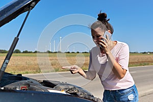 Car breakdown, unhappy woman on the road talking on mobile phone