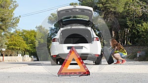 Car breakdown. Woman changing tire on a road