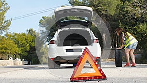 Car breakdown. Woman changing tire on a road