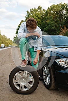 Car breakdown, young man puts the spare tyre
