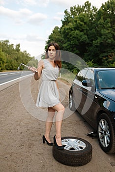 Car breakdown, young woman puts the spare tyre