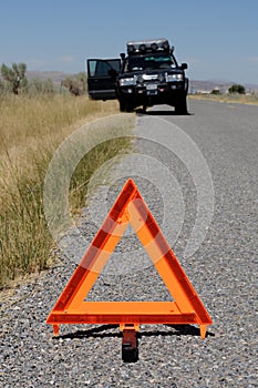 Car broken down on road with warning triangle