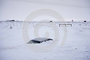 Car buried to its roof in deep snow not far from the road. North Dakota, USA