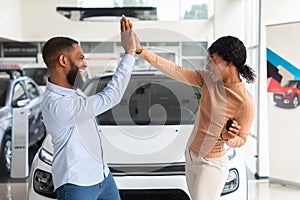 Car Buyers. Excited Black Spouses Celebrating Purchasing New Vehicle In Dealership Center