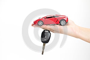 Car buying concept. A hand holding a car key with a toy car on a white background