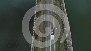 A car with a camper rides on road across a river in Iceland. Family Trip. Aerial