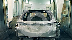 Car carcass is getting sprayed with zinc in a factory unit