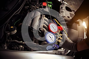 Car care maintenance and service, Hand technician auto mechanic using measuring manifold gauge check refrigerant and filling car