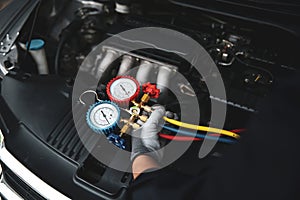 Car care maintenance and service, Hand technician auto mechanic using measuring manifold gauge check refrigerant and filling car