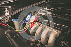 Car care maintenance and servicing, Close-up measuring manifold gauge on car engine for check refrigerant and filling air