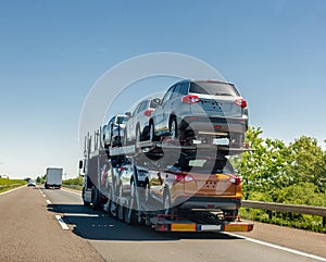 Car carrier trailer with cars on bunk platform. Car transport truck on the highway