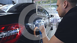In the car center in the garage, professionals polish a new sports car. Luxury car polishing. Concept of: Racing, Sport car, New